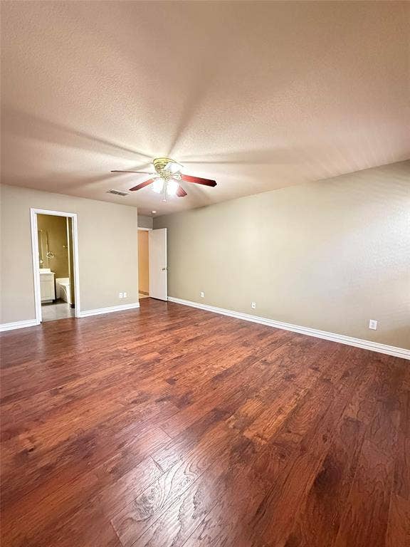 Room featuring wood-finish flooring, neutral wall paint, and a ceiling-mounted light fixture with a fan