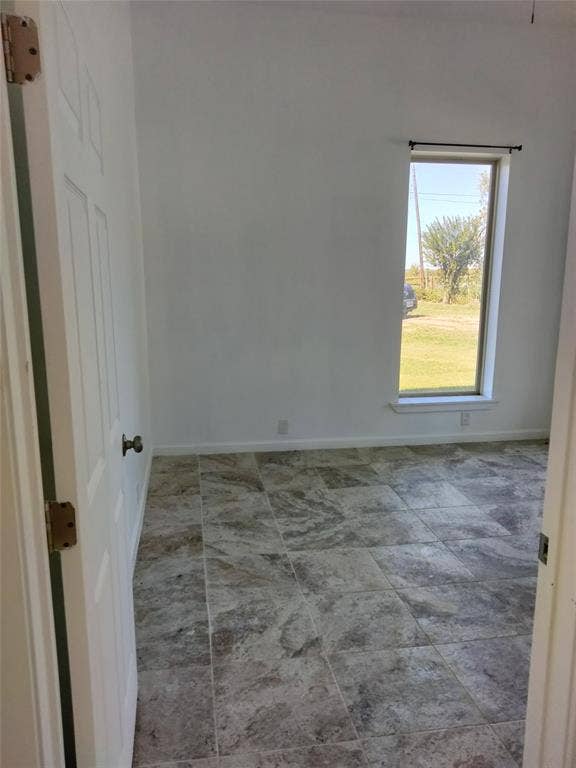 Interior room featuring neutral wall finishes, large-format stone-patterned tile flooring, and a single vertical window