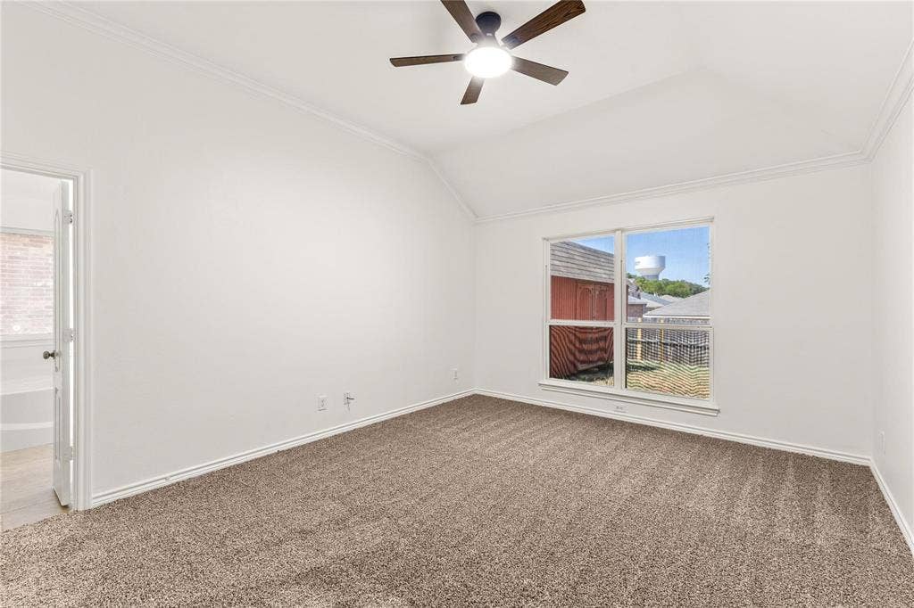 Vaulted ceiling featuring a ceiling fan with integrated lighting, neutral wall-to-wall carpeting, and a double-pane window