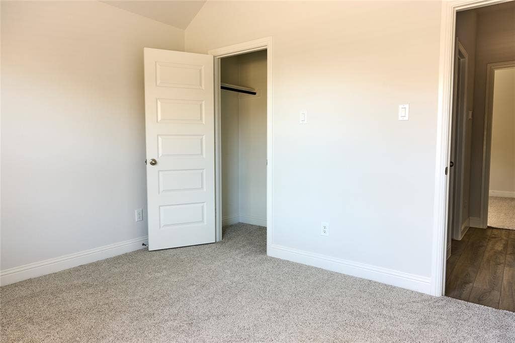 Neutral wall tones, carpeting, and five-panel interior door with a closet containing a built-in rod