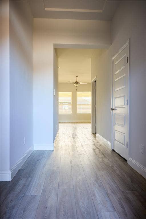 Hallway featuring wood-finish flooring, white walls, and a five-panel interior door