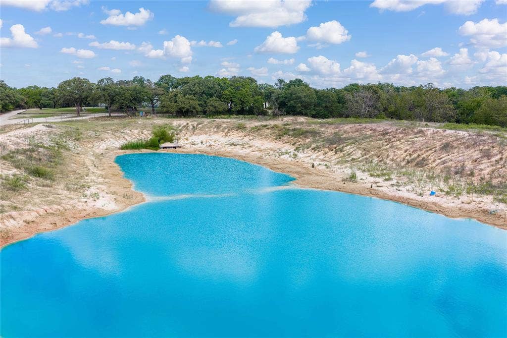 5540 County Road 334, Blanket, TX 76432 Expansive pond featuring natural shoreline, sandy banks, and surrounding mature trees