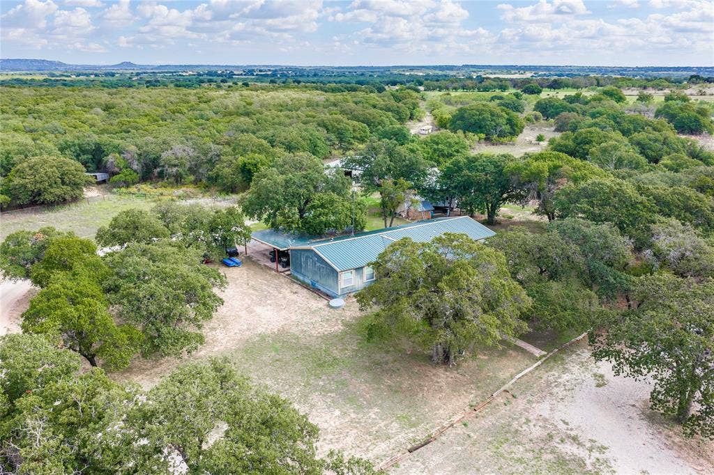 5540 County Road 334, Blanket, TX 76432 Residential property featuring a metal roof, an attached carport, and extensive surrounding acreage with mature trees