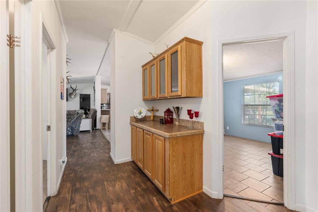 5540 County Road 334, Blanket, TX 76432 Hallway featuring built-in cabinetry with wood-finish doors, glass-fronted upper cabinets, and a solid-surface countertop