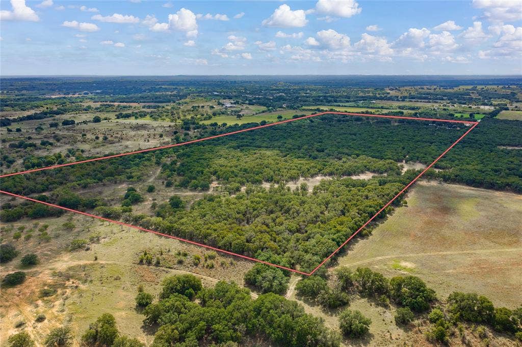 5540 County Road 334, Blanket, TX 76432 Expansive undeveloped acreage featuring diverse terrain, clusters of mature trees, and open meadow space