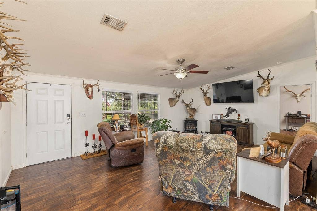 5540 County Road 334, Blanket, TX 76432 Living area featuring wood-finish flooring, white panel door, multi-pane windows, and a ceiling fan with integrated lighting
