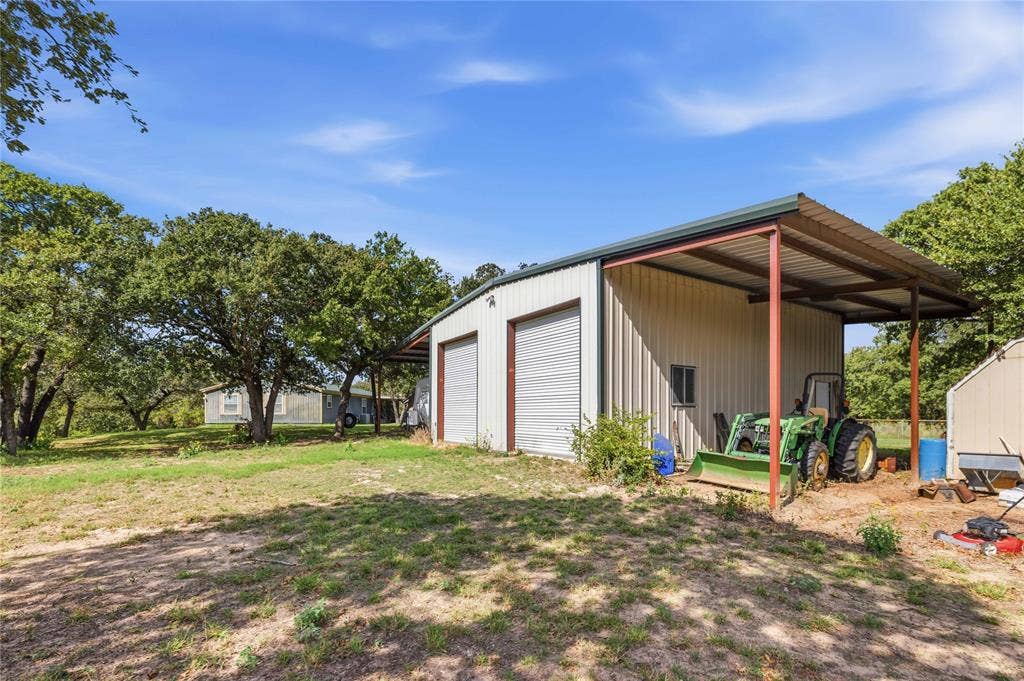 5540 County Road 334, Blanket, TX 76432 Metal-sided workshop featuring two roll-up doors and a covered carport extension