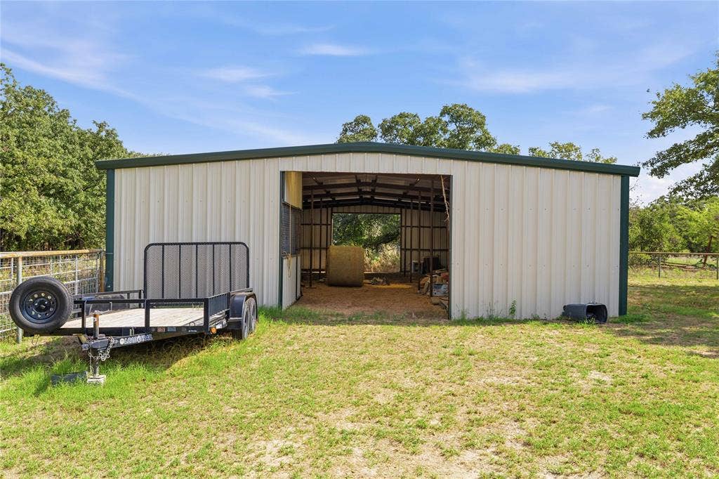 5540 County Road 334, Blanket, TX 76432 Metal-clad agricultural structure featuring a wide open-entry bay, exposed steel framing, and an earthen interior floor