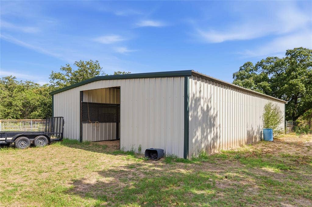 5540 County Road 334, Blanket, TX 76432 Metal-sided agricultural structure featuring a covered stall, corrugated metal siding, and a low-pitch roof
