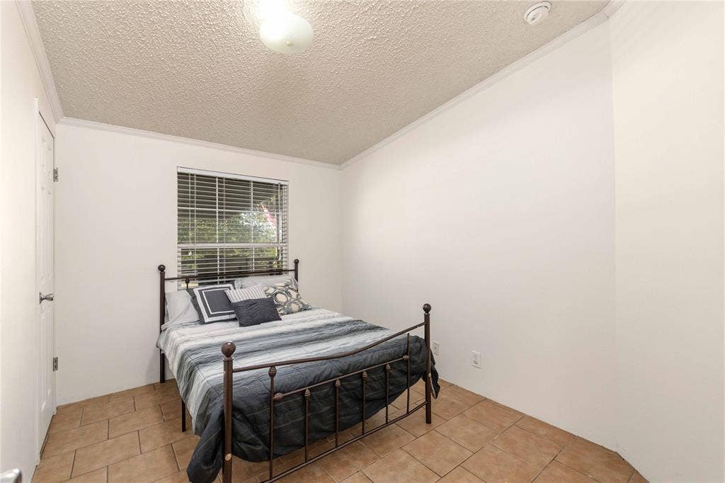 5540 County Road 334, Blanket, TX 76432 Room with neutral walls, tiled flooring, textured ceiling, and a window fitted with horizontal blinds