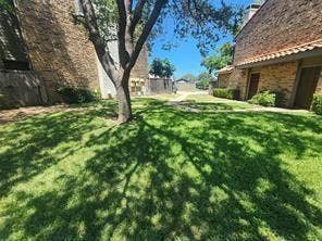 14800 Enterprise Drive, #22D, Farmers Branch, TX 75234 Exterior courtyard featuring brick masonry, a central mature tree, a manicured lawn, and a paved walkway