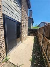 14800 Enterprise Drive, #22D, Farmers Branch, TX 75234 Exterior featuring a stone veneer facade, horizontal siding, sliding glass door, concrete walkway, and wood privacy fencing