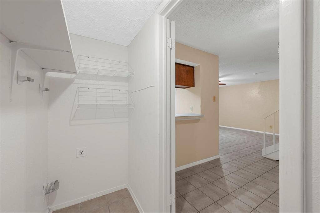 14800 Enterprise Drive, #22D, Farmers Branch, TX 75234 Utility space featuring wall-mounted wire shelving, tile flooring, and dedicated electrical and plumbing connections