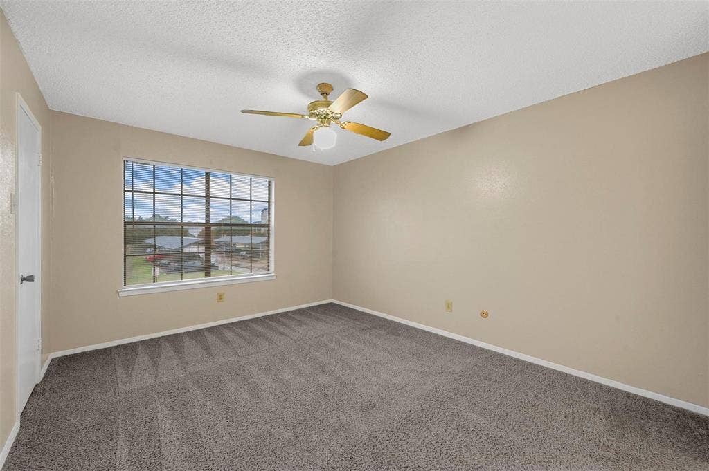 14800 Enterprise Drive, #22D, Farmers Branch, TX 75234 Neutral-toned interior space featuring wall-to-wall carpeting, multi-pane window, and a ceiling fan with integrated light fixture
