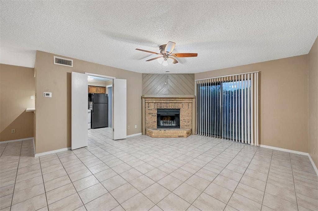 14800 Enterprise Drive, #22D, Farmers Branch, TX 75234 Corner fireplace featuring brick masonry and a raised hearth, tile flooring, ceiling fan, and sliding glass doors