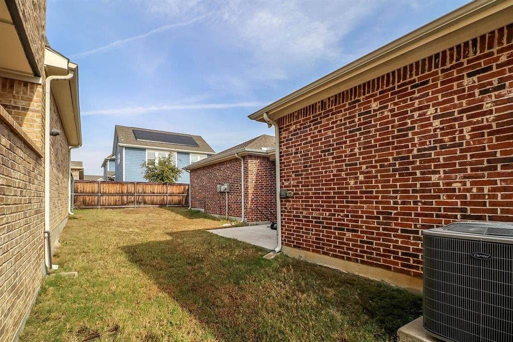 Exterior side yard featuring brick masonry construction, a concrete patio, and a wood privacy fence