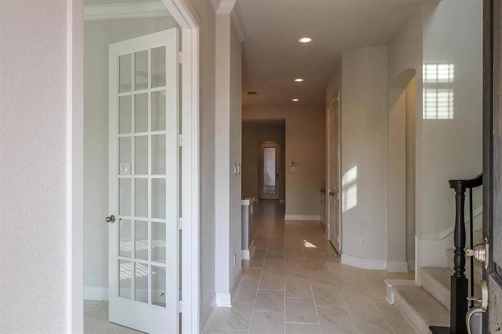 Interior entry featuring large-format tile flooring, recessed lighting, arched doorways, a white French door, and a staircase with a dark wood handrail