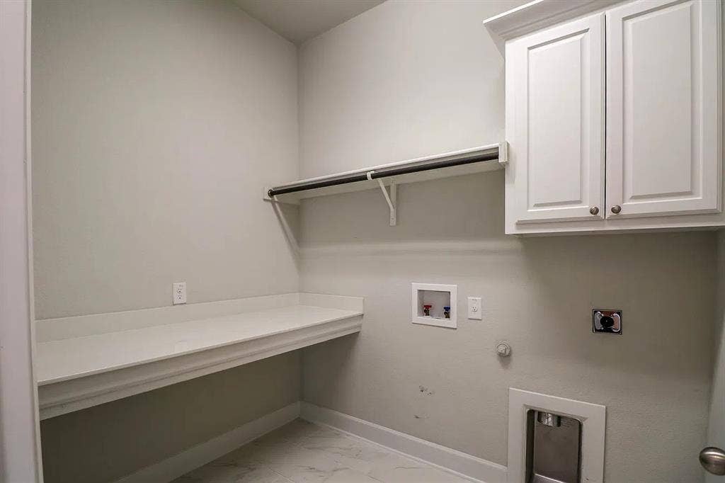 Utility space featuring white shaker-style upper cabinetry, an integrated folding counter, a mounted clothing rod, and tile flooring