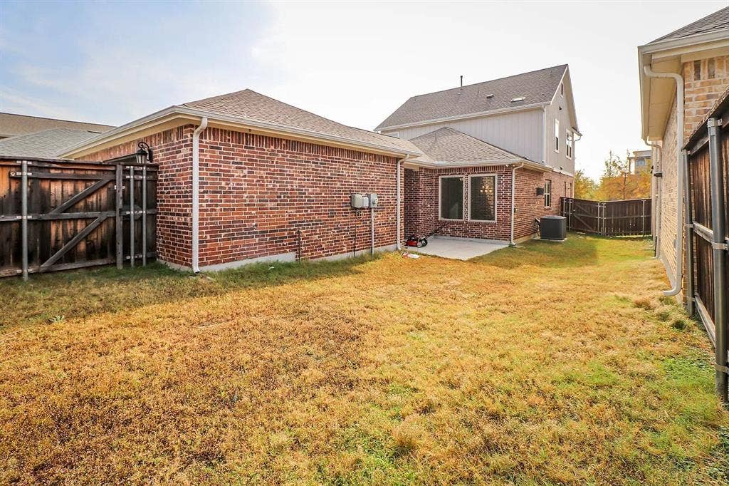 Rear exterior featuring brick masonry siding, concrete patio, and wood privacy fencing