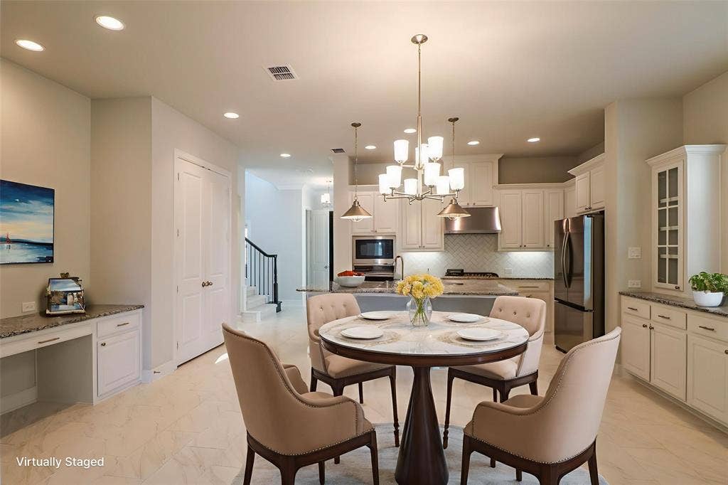 Kitchen featuring stone countertops, white shaker-style cabinetry, stainless steel appliances, a multi-light chandelier, and recessed lighting