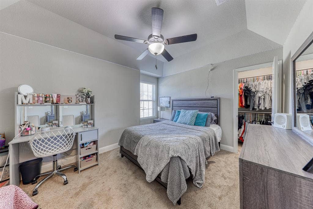 128 Breeders Drive, Willow Park, TX 76087 Tray ceiling featuring a central ceiling fan with integrated lighting, neutral wall tones, carpeted flooring, and a walk-in closet