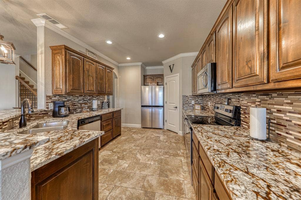 128 Breeders Drive, Willow Park, TX 76087 Kitchen featuring wood cabinetry, stone-surface countertops, tile backsplash, stainless steel appliances, and tile flooring