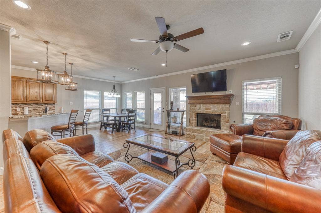 128 Breeders Drive, Willow Park, TX 76087 Open-concept living area featuring a stone-faced fireplace with a natural wood mantel, recessed lighting, ceiling fan, and tile flooring