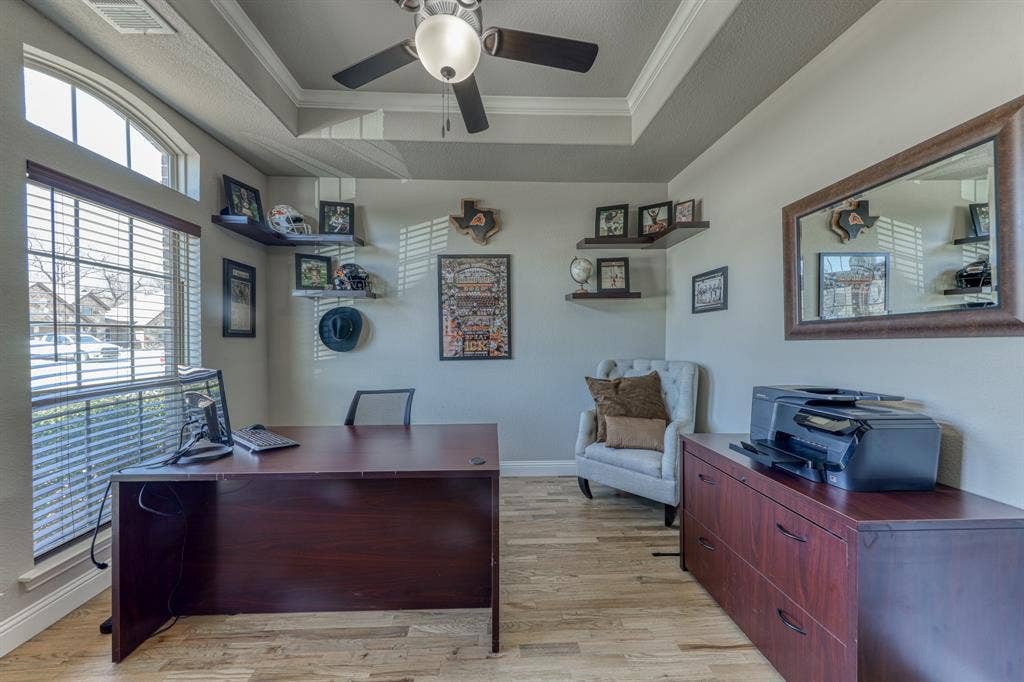 128 Breeders Drive, Willow Park, TX 76087 Tray ceiling with crown molding, wood-finish flooring, ceiling fan with integrated light fixture, large arched window, and wall-mounted floating shelves