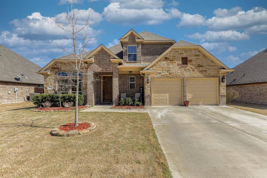 128 Breeders Drive, Willow Park, TX 76087 Exterior facade featuring a combination of brick and stone masonry, two-car garage, and arched window detailing