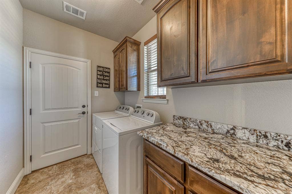 128 Breeders Drive, Willow Park, TX 76087 Laundry area featuring raised-panel wood cabinetry, natural stone countertops, tile flooring, and a single-panel interior door