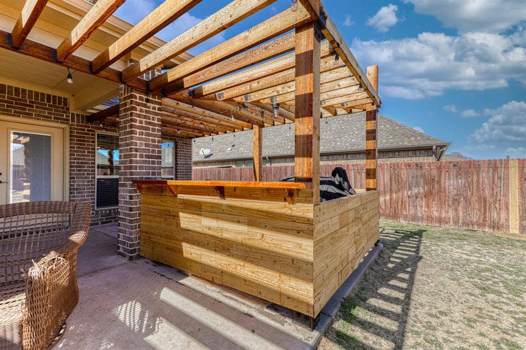 128 Breeders Drive, Willow Park, TX 76087 Outdoor space featuring a built-in wooden bar with an overhead pergola, brick exterior siding, concrete patio, and a wood privacy fence