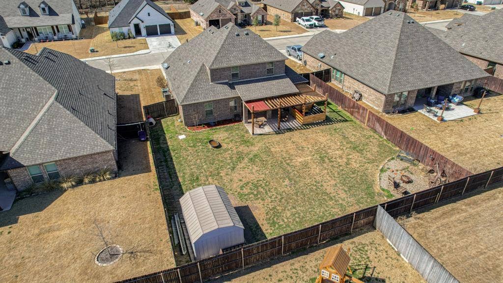128 Breeders Drive, Willow Park, TX 76087 Fenced backyard featuring a wood-frame pergola, a detached metal storage structure, and a perimeter wood fence