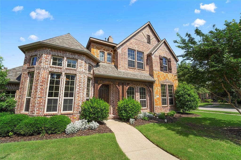 Multi-story exterior featuring a brick and stone facade, steep rooflines, wooden architectural detailing at the entry, and a paved walkway