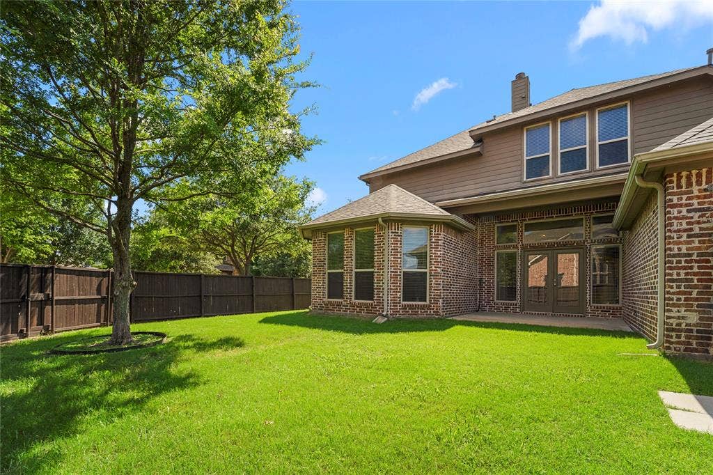 Exterior featuring brick and horizontal siding, a bay window configuration, double-glass entry doors, and a wood privacy fence