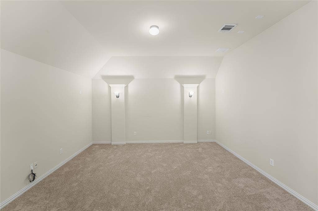 Interior space featuring neutral wall tones, plush wall-to-wall carpeting, two decorative structural columns with built-in wall sconces, and recessed ceiling lighting