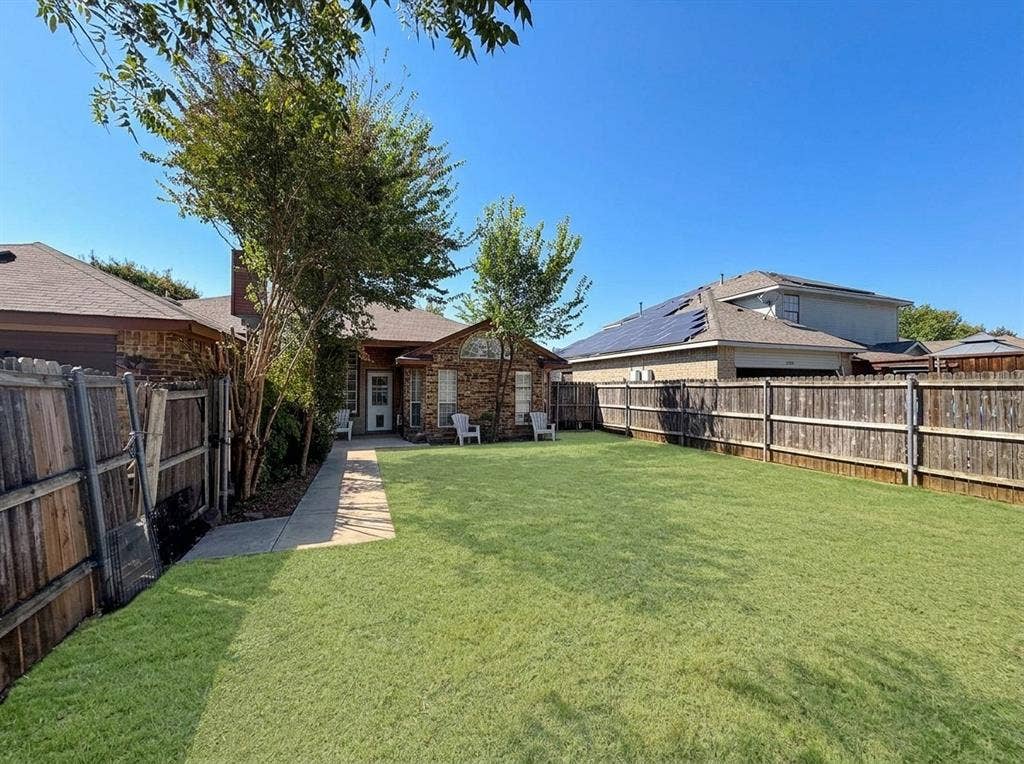 2306 Summit Drive, McKinney, TX 75071 Fenced backyard featuring a manicured lawn, mature trees, and a concrete pathway