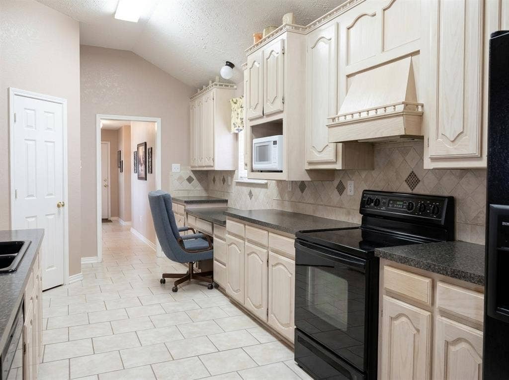 2306 Summit Drive, McKinney, TX 75071 Kitchen featuring arched-panel cabinetry, vaulted ceiling, stone-finish countertops, ceramic tile flooring, and a built-in range hood