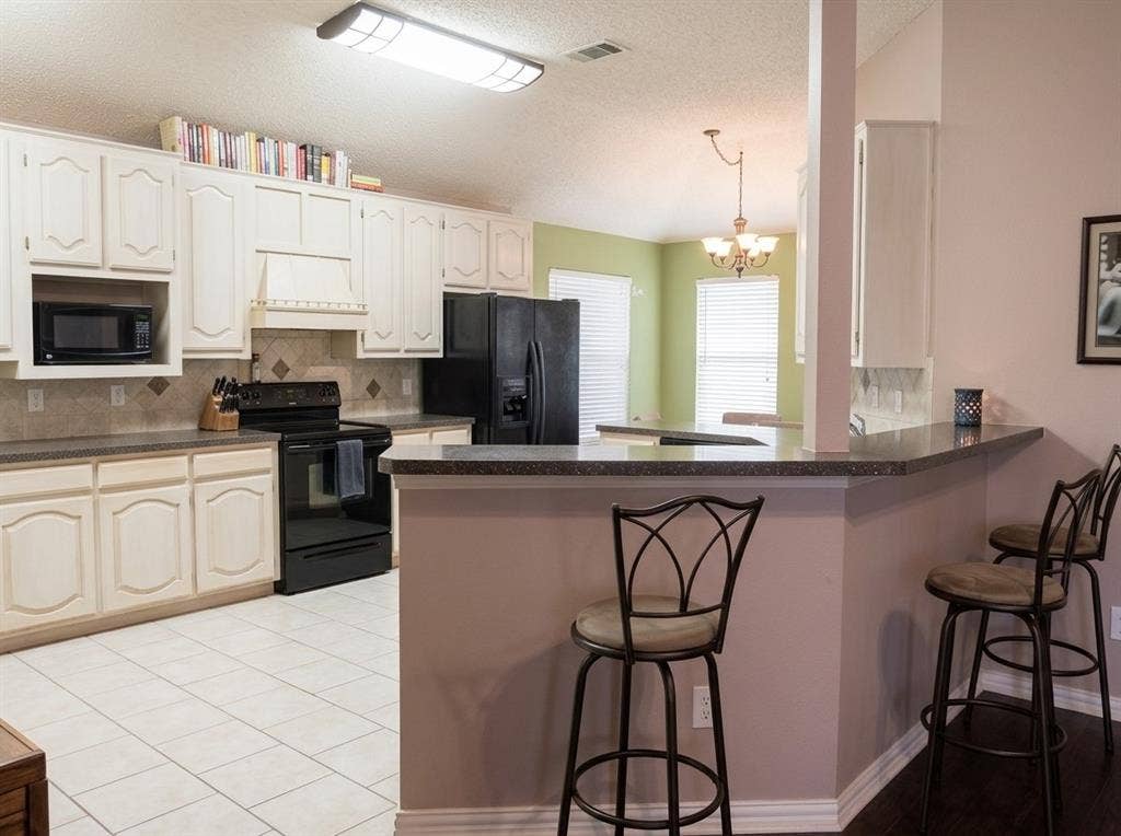 2306 Summit Drive, McKinney, TX 75071 Kitchen featuring white raised-panel cabinetry, stone-composite countertops, tile backsplash, built-in microwave, and breakfast bar