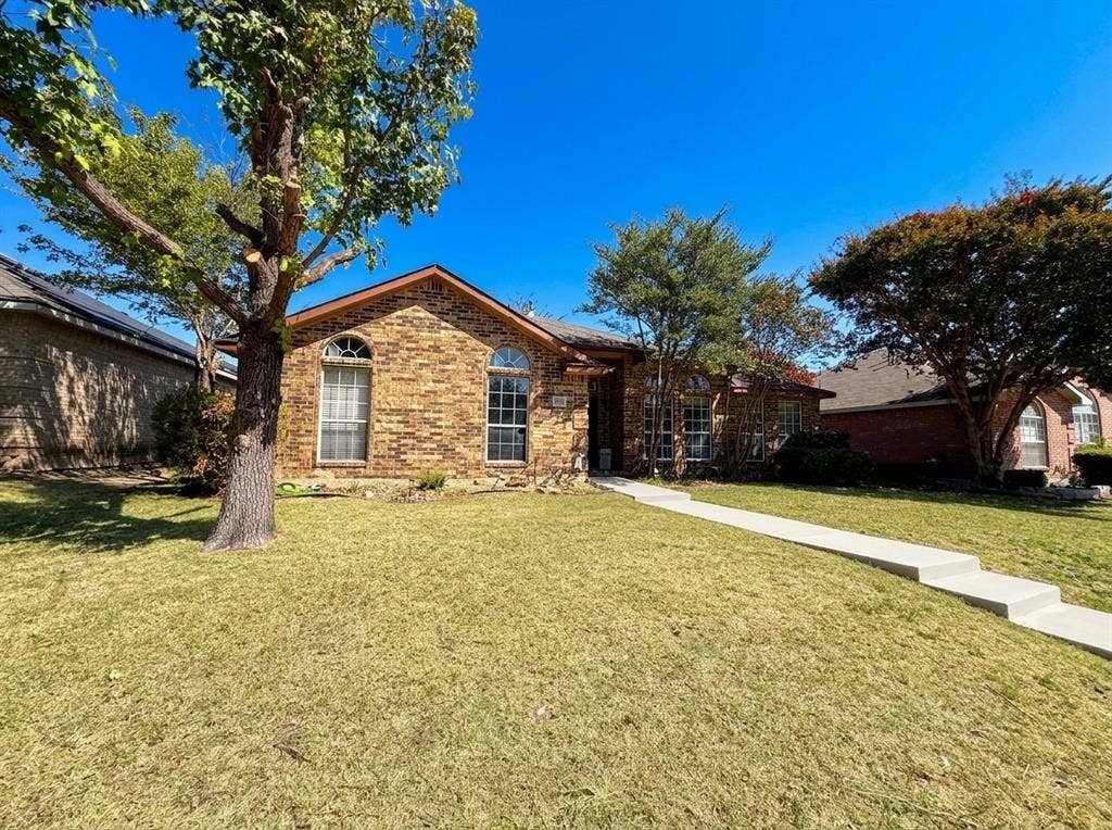 2306 Summit Drive, McKinney, TX 75071 Brick exterior featuring arched windows, a pitched roof, and a concrete walkway