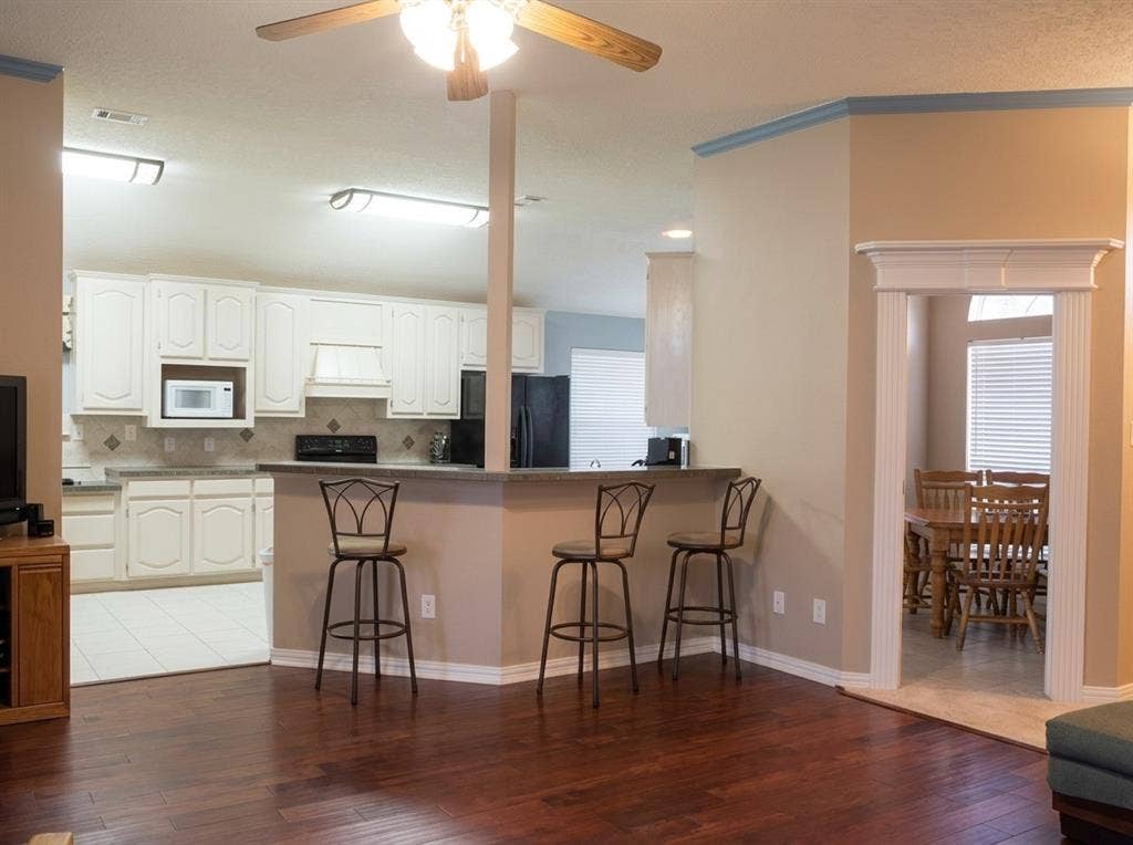 2306 Summit Drive, McKinney, TX 75071 Kitchen featuring white cabinetry, solid-surface countertops, and a breakfast bar