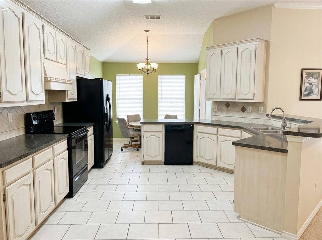 2306 Summit Drive, McKinney, TX 75071 Kitchen featuring white raised-panel cabinetry, dark countertops, a vaulted ceiling, tiled flooring, and a multi-light chandelier