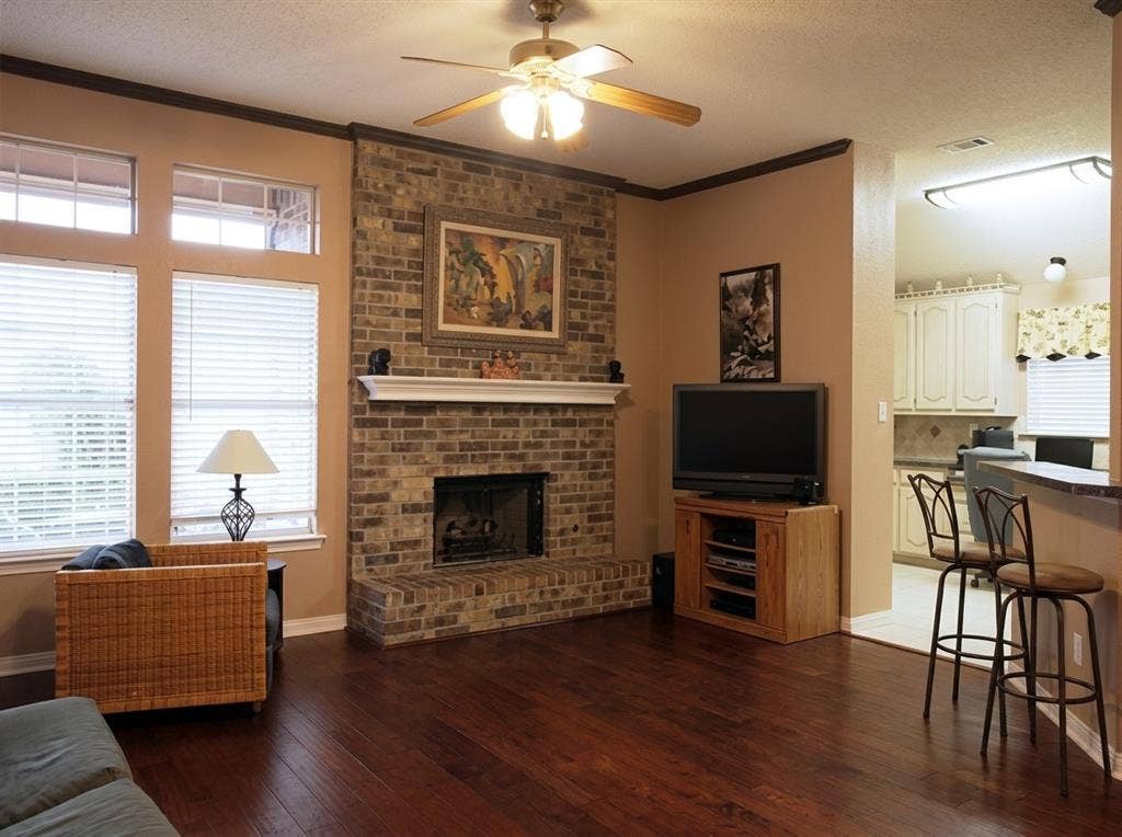 2306 Summit Drive, McKinney, TX 75071 Floor-to-ceiling brick fireplace with a custom mantel, wood-finish flooring, and crown molding