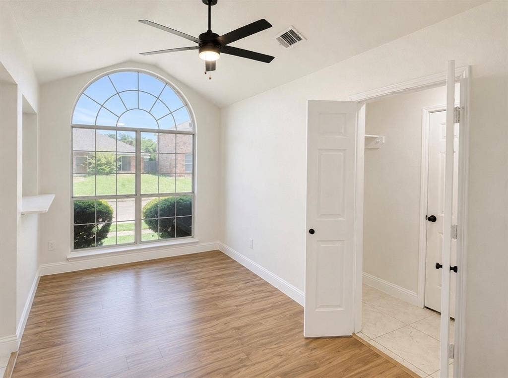 2400 Waterloo Lane, Mesquite, TX 75181 Vaulted ceiling featuring an arched window, wood-finish flooring, and a matte black ceiling fan