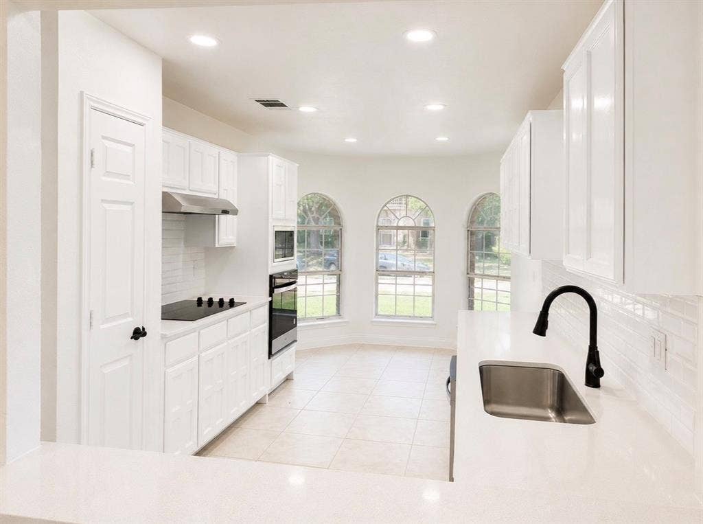 2400 Waterloo Lane, Mesquite, TX 75181 Kitchen featuring white cabinetry, quartz countertops, subway tile backsplash, stainless steel appliances, and arched windows