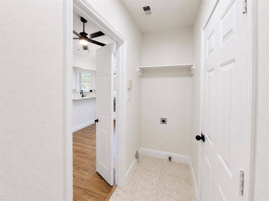 2400 Waterloo Lane, Mesquite, TX 75181 Dedicated utility area featuring tile flooring, a wall-mounted storage shelf, and crisp white paneled doors with matte black hardware