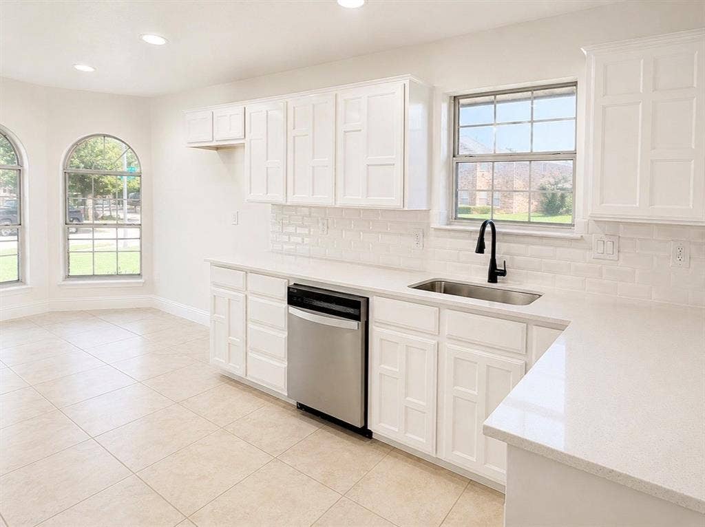 2400 Waterloo Lane, Mesquite, TX 75181 Kitchen featuring white cabinetry, subway tile backsplash, light-toned countertops, stainless steel dishwasher, and arched windows