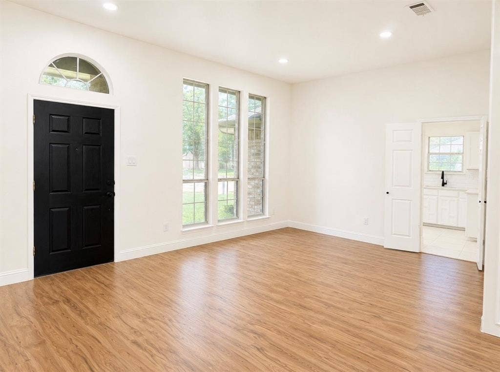 2400 Waterloo Lane, Mesquite, TX 75181 Interior room featuring wood-finish flooring, recessed lighting, a contrasting black entry door with an arched transom window, and triple vertical windows