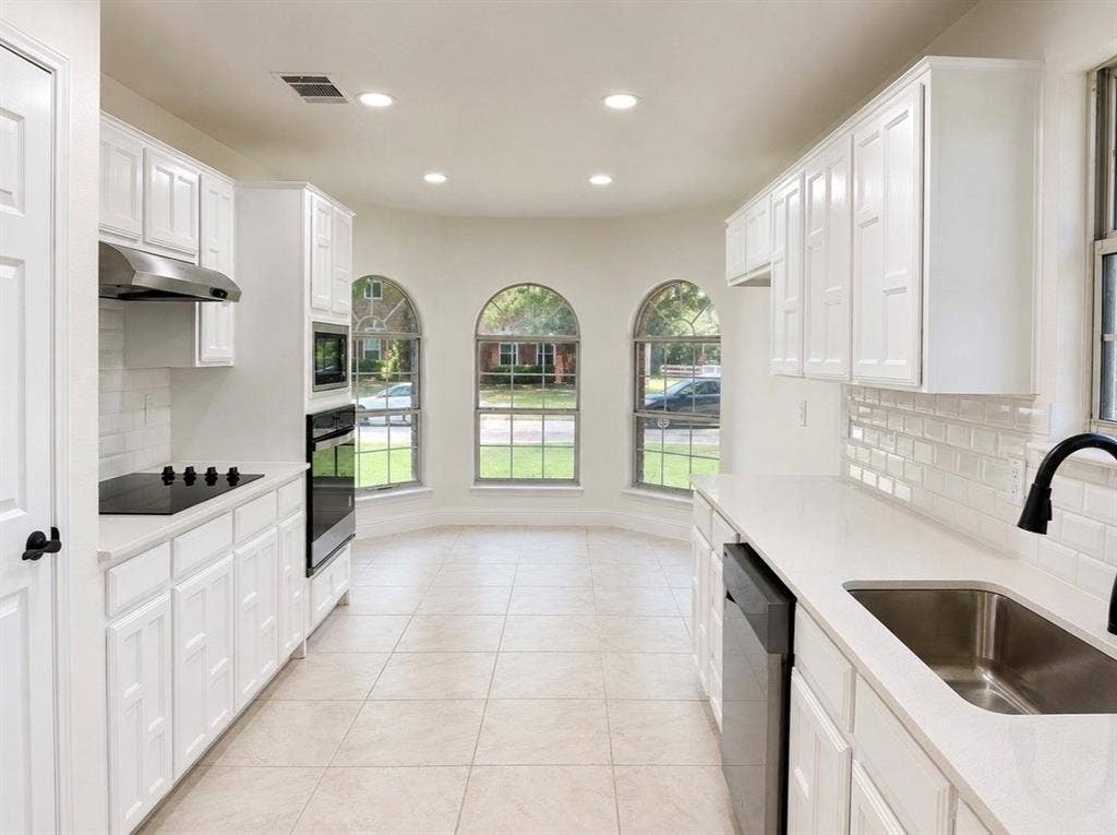 2400 Waterloo Lane, Mesquite, TX 75181 Kitchen featuring white cabinetry, subway tile backsplash, solid-surface countertops, stainless steel appliances, and arched windows