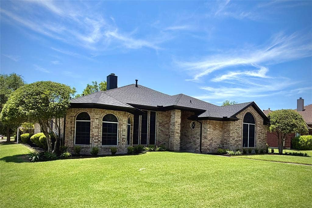 2400 Waterloo Lane, Mesquite, TX 75181 Single-story brick exterior featuring a hip roof, arched windows, and a manicured lawn
