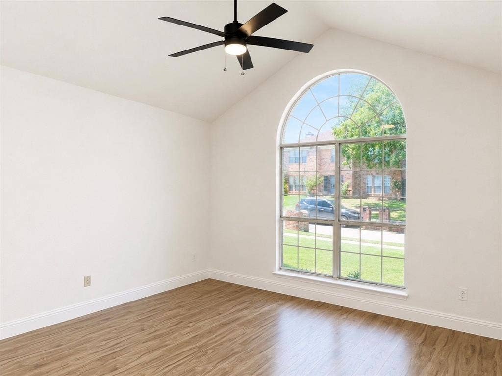 2400 Waterloo Lane, Mesquite, TX 75181 Vaulted ceiling with an arched window, wood-finish flooring, and a matte black ceiling fan with integrated lighting